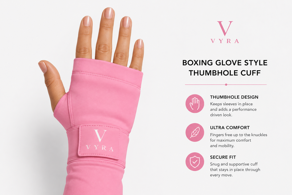 A pink boxing glove style thumbhole cuff worn on a hand, shown against a light gray background with product text and feature callouts on the right. The cuff has a visible VYRA logo patch.